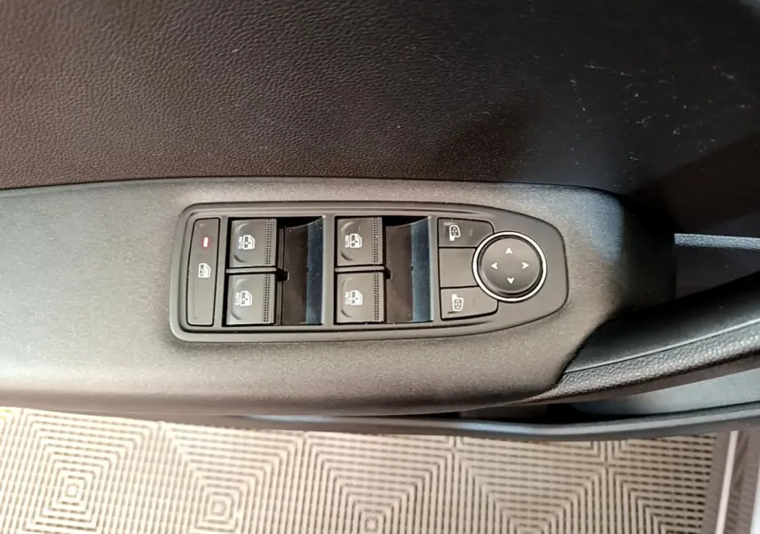 Gros plan sur les commandes des vitres électriques et rétroviseurs sur la porte côté conducteur d’un Renault Captur gris foncé.