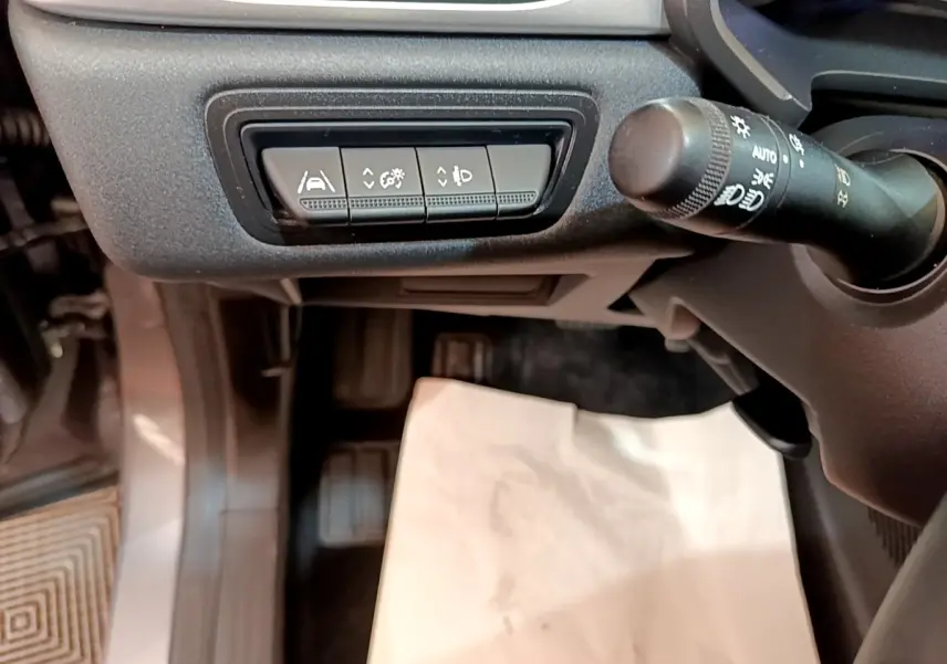 Détail du tableau de bord côté gauche du Renault Captur gris foncé, avec commandes d'assistance et commande de phares.