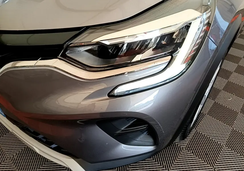 Gros plan sur le phare avant droit du Renault Captur Zen E-Tech hybride gris foncé, avec feux LED et partie de la calandre visible.