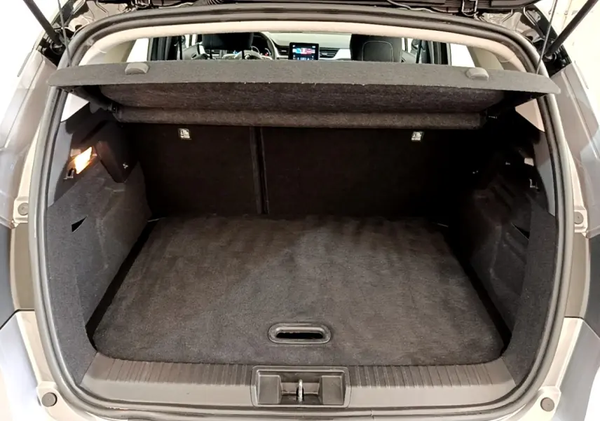 Coffre ouvert vu de l'arrière d'un Renault Captur Zen E-Tech hybride gris foncé, intérieur noir et tablette de coffre visible.