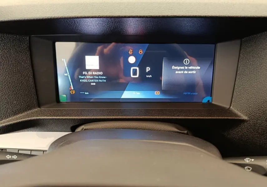 Vue rapprochée du tableau de bord numérique du Peugeot Expert Fourgon XL noir, affichant la radio et les alertes.