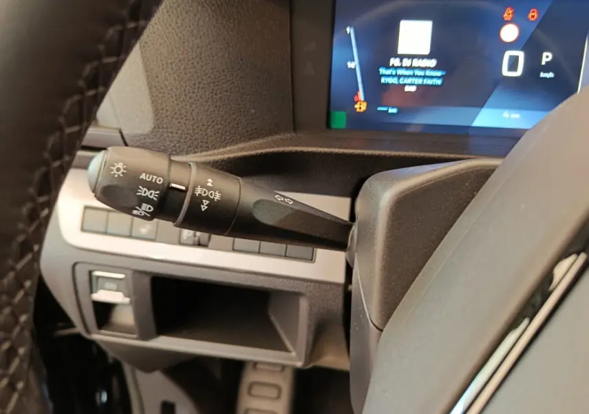 Gros plan sur la manette des feux et clignotants du Peugeot Expert Fourgon noir, avec tableau de bord numérique en arrière-plan.