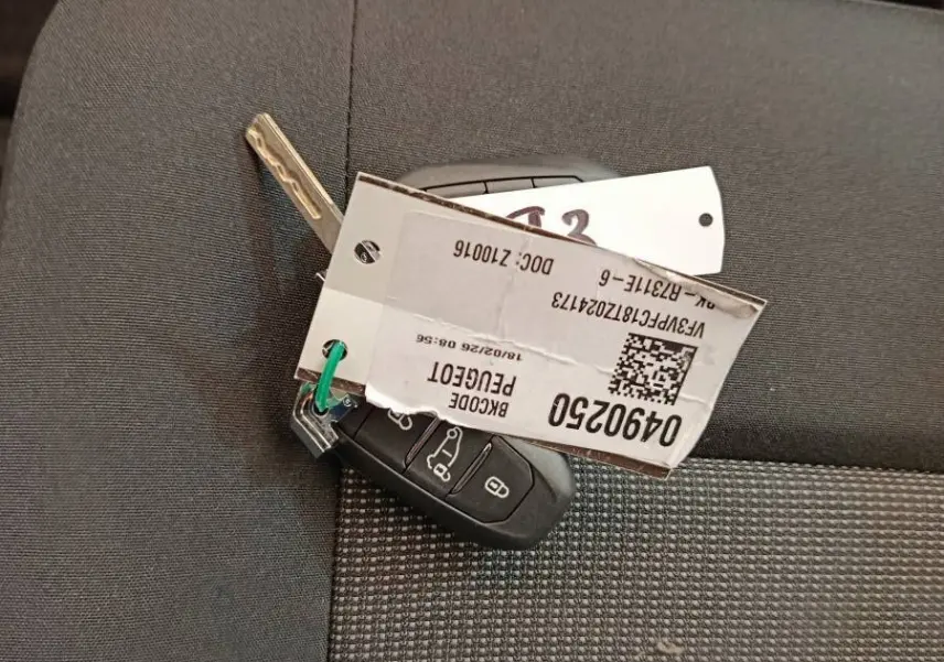 Clé de Peugeot Expert Fourgon XL Diesel noire posée sur un siège tissu gris à motifs.