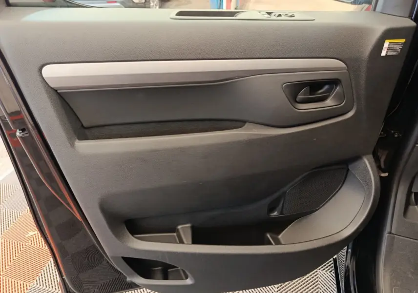 Vue rapprochée de la porte avant droite noire du Peugeot Expert Fourgon XL Diesel 2026 avec poignée et rangements intégrés.