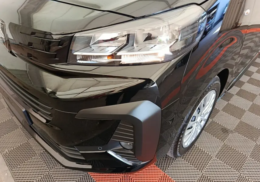 Gros plan sur l'avant droit noir brillant du Peugeot Expert Fourgon XL Diesel 2026 avec phares allumés et jante visible.