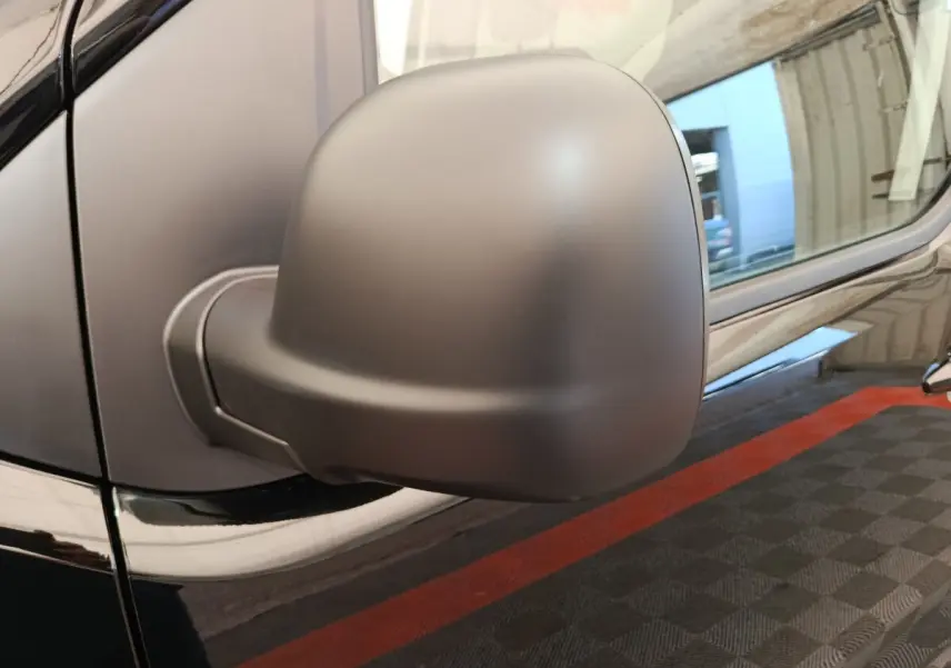 Gros plan sur le rétroviseur côté gauche du Peugeot Expert Fourgon XL noir, avec reflet de l’environnement sur la carrosserie.
