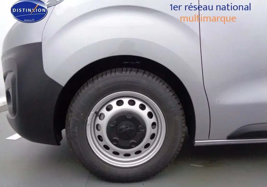 Gros plan sur la roue avant gauche d'un Peugeot Expert gris Artense métal avec jante en alliage et pare-chocs noir.