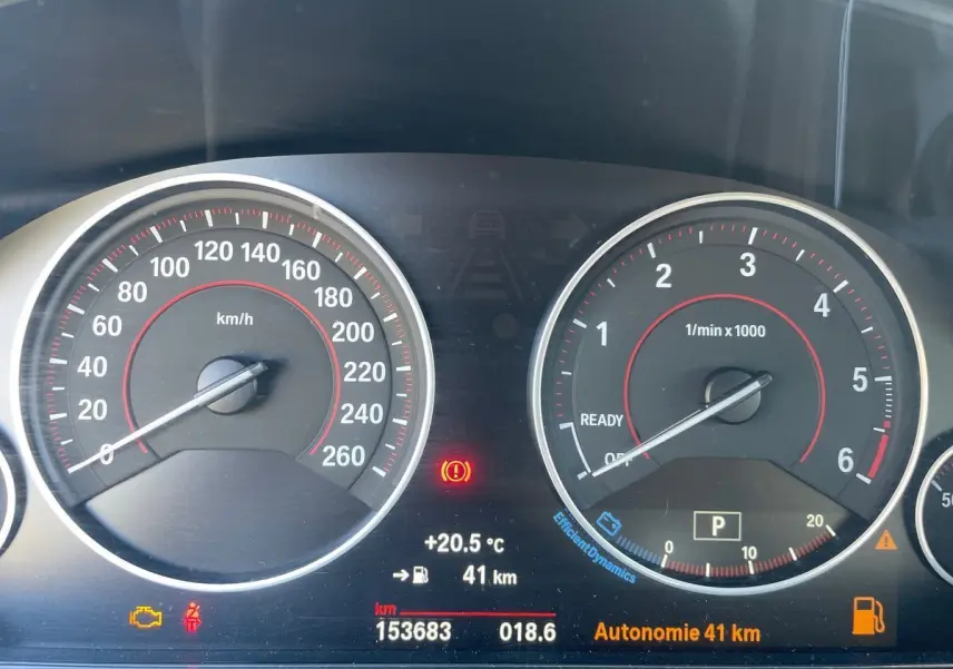 Tableau de bord de BMW Série 3 Touring F31 blanc, vue rapprochée des compteurs avec affichage digital et voyants allumés.