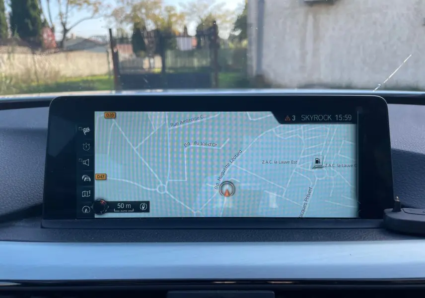 Écran de navigation GPS allumé sur le tableau de bord d'une BMW Série 3 Touring F31 blanche, vue intérieure.