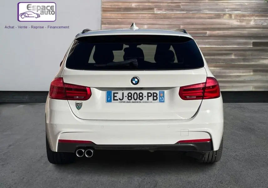 Vue arrière d'une BMW Série 3 Touring F31 blanche, version 330DA XDrive M Sport avec double sortie d'échappement à gauche.
