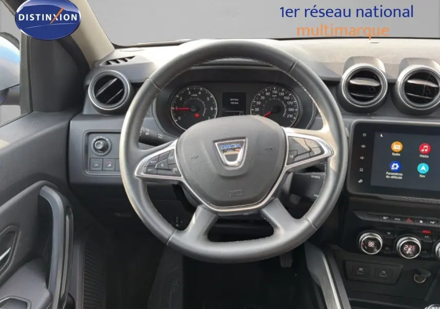 Vue intérieure centrée sur le volant du Dacia Duster 2022, tableau de bord et écran tactile visibles.