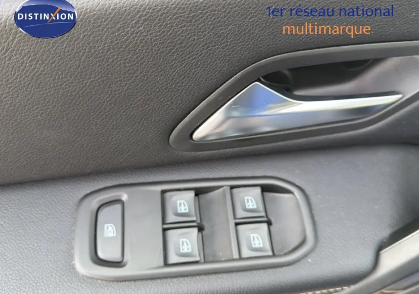 Détail des commandes des vitres et poignée de porte intérieure en plastique noir du Dacia Duster 2022.