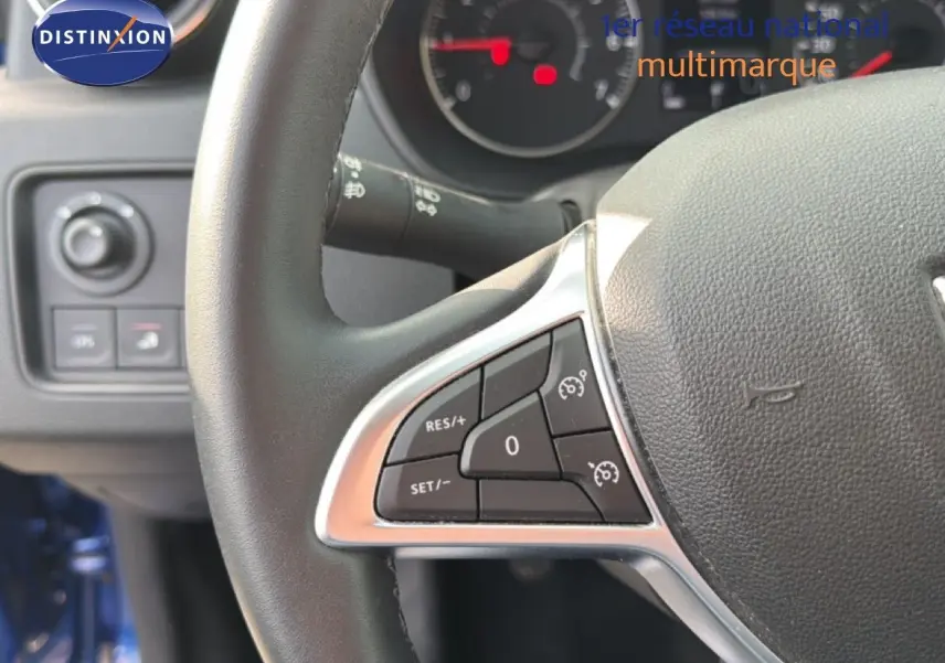 Gros plan sur le volant côté gauche du Dacia Duster 2022 bleu Iron, avec commandes de régulateur de vitesse visibles.