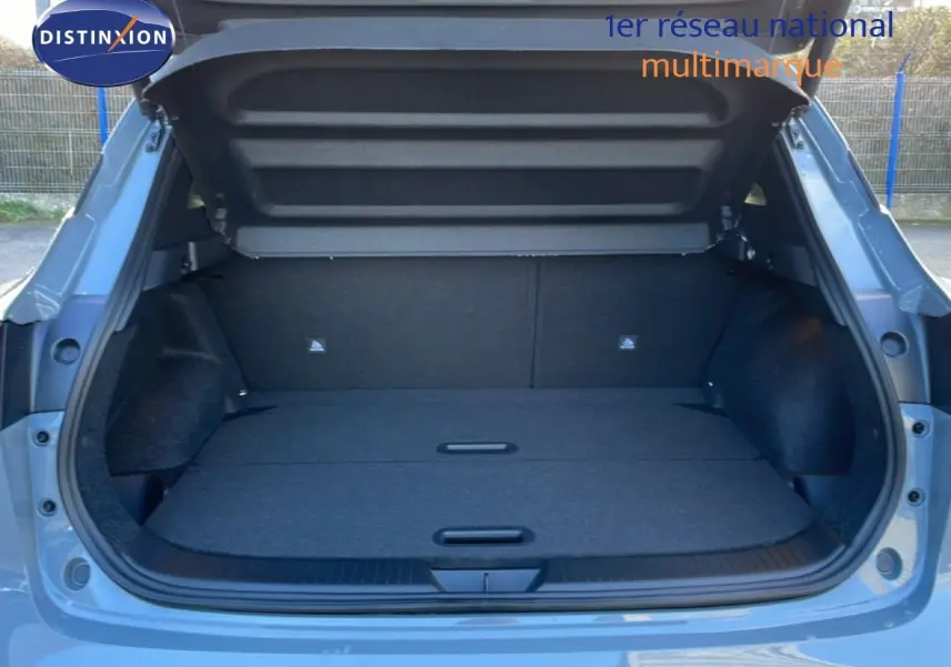 Coffre ouvert vu de l'arrière d'un Nissan Qashqai 2025 gris argile métal, montrant un espace de chargement spacieux et propre.