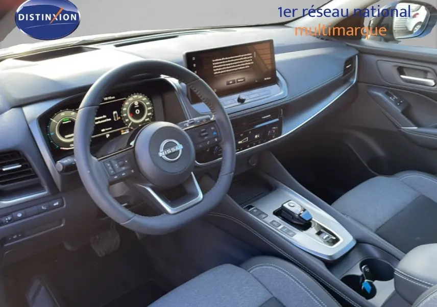 Vue intérieure côté conducteur du Nissan Qashqai gris argile, mettant en valeur le tableau de bord digital et la console centrale moderne.