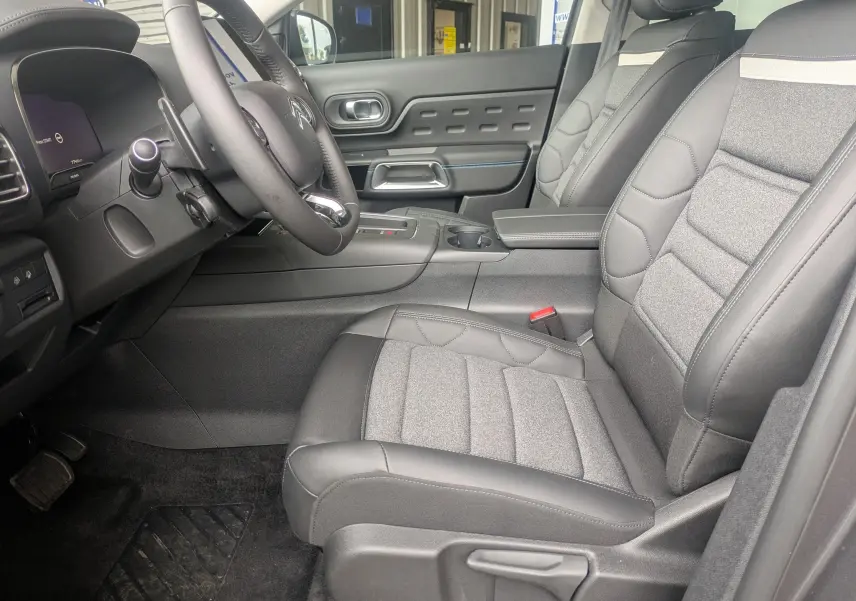 Vue intérieure côté conducteur du Citroën C5 Aircross 2025, sièges tissu et cuir gris avec volant multifonction croûte de cuir.