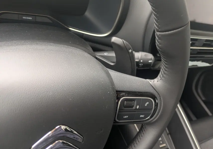 Gros plan sur le volant cuir noir du Citroën C5 Aircross hybride 2025 avec commandes audio intégrées.