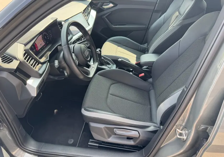 Intérieur gris de l'Audi A1 Sportback 2019, vue côté conducteur, volant multifonction et sièges sport en tissu et cuir.