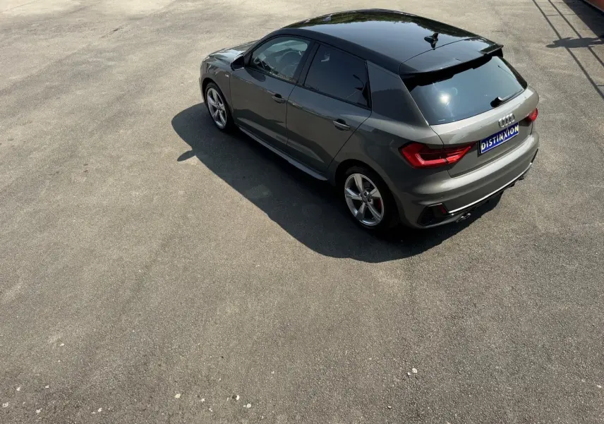 Audi A1 Sportback gris vue 3/4 arrière droit, avec toit noir brillant et jantes alliage sport.