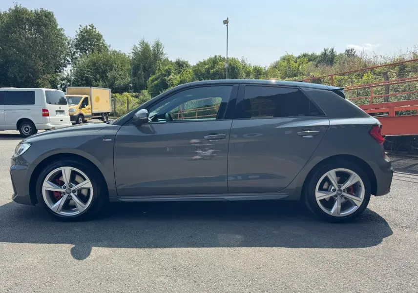 Profil côté gauche d'une Audi A1 Sportback gris métallisé de 2019 avec jantes alliage et étriers rouges.