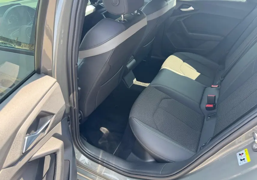 Vue intérieure arrière côté gauche de l'Audi A1 Sportback gris 2019, sièges en cuir noir et tissu perforé.