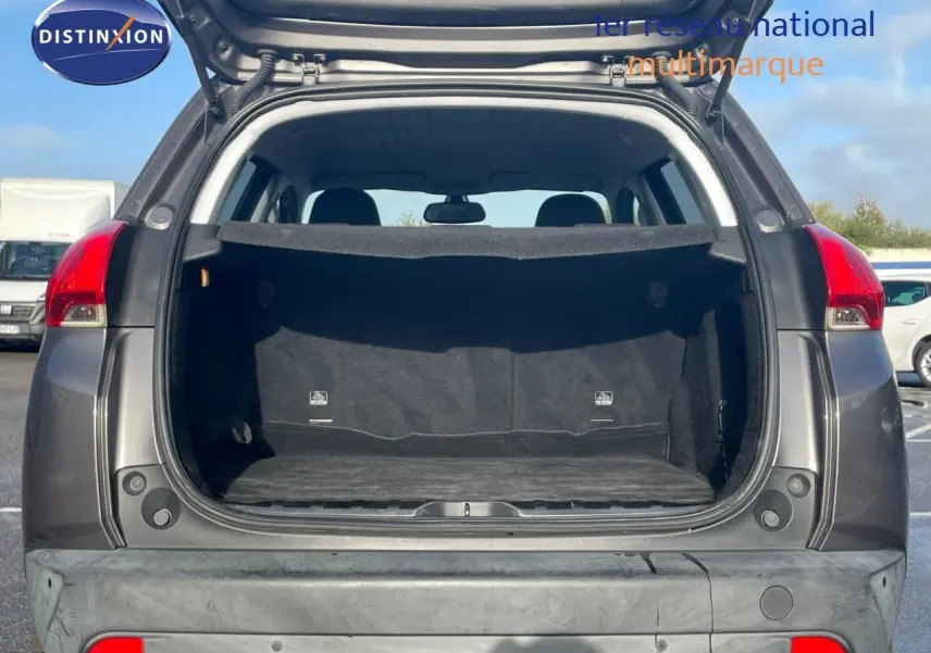 Coffre ouvert d'un Peugeot 2008 gris platinium métal, vue arrière montrant l'espace de chargement vide.