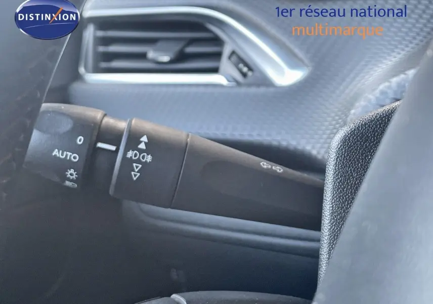 Gros plan sur la commande des phares et clignotants à gauche du volant dans l'habitacle d'un Peugeot 2008 gris platinium.