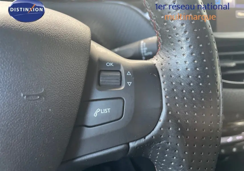 Gros plan sur le volant en cuir noir perforé du Peugeot 2008 1.2 PureTech 110ch Crossway gris platinium, avec commandes intégrées.