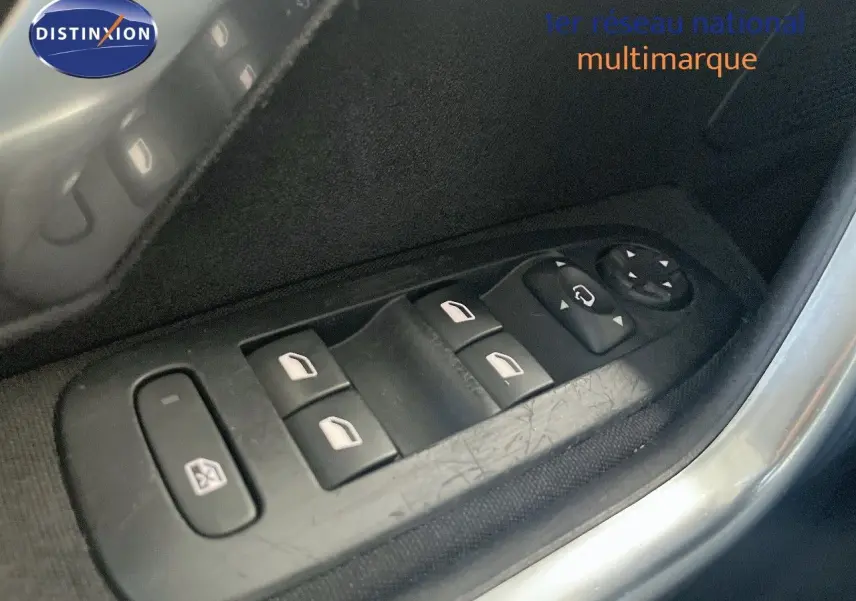 Gros plan sur les commandes des vitres électriques et des rétroviseurs côté conducteur d'une Peugeot 2008 gris platinium.