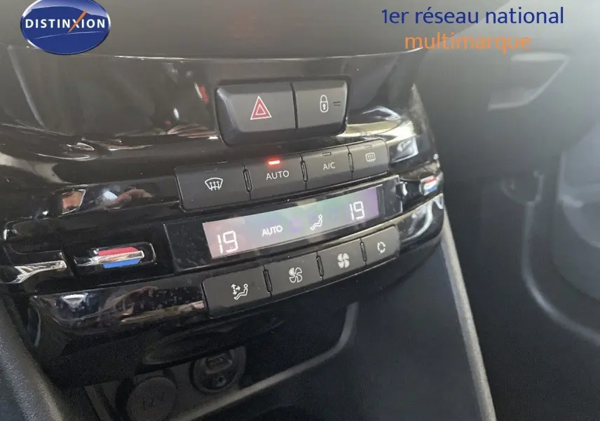 Gros plan sur la console centrale noire du Peugeot 2008 2019 montrant les commandes de climatisation automatique et les boutons d'alerte et verrouillage.