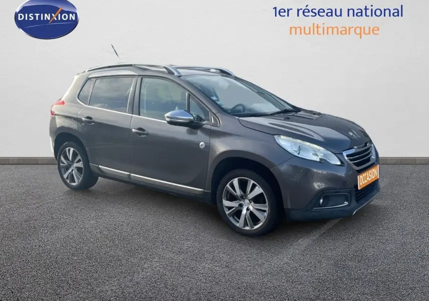 Peugeot 2008 gris platinium métal en 3/4 avant droit, avec jantes alliage et barres de toit visibles.