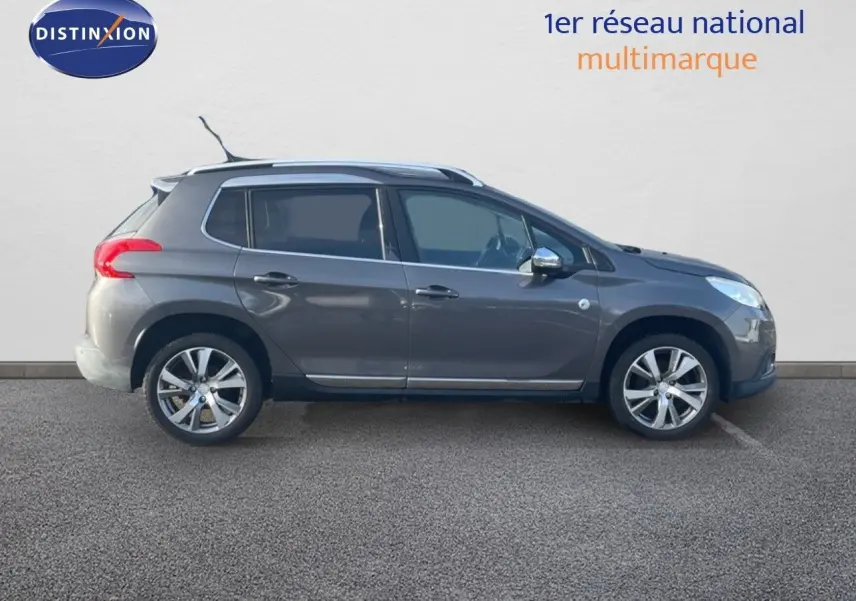 Profil côté gauche d'un Peugeot 2008 gris platinium métallisé de 2019 avec jantes alliage et barres de toit.
