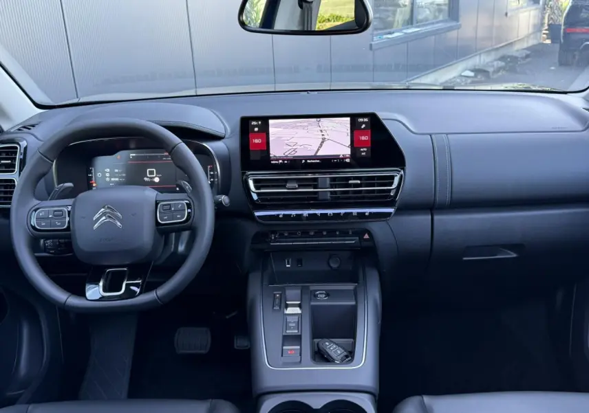Intérieur noir du Citroën C5 Aircross 2025 vu de face, tableau de bord moderne avec écran tactile central et volant multifonction.