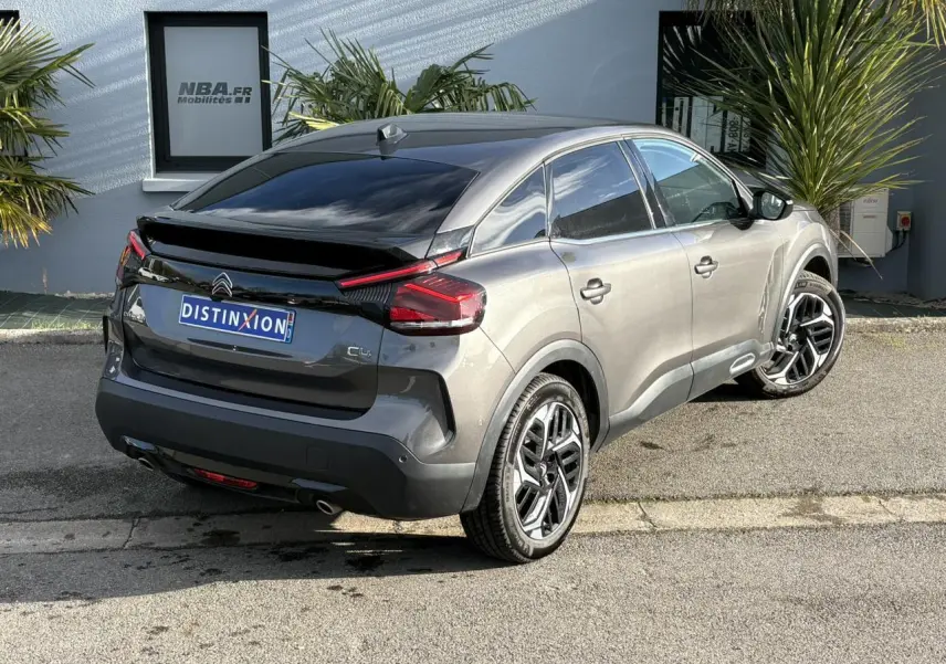 Vue 3/4 arrière droite d'une Citroën C4 2024 gris Platinium avec jantes alliage 18'' et toit noir brillant.