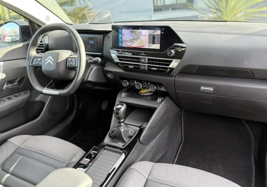 Vue intérieure côté conducteur de la Citroën C4 2024, montrant le volant cuir, écran tactile 10" et levier de vitesses manuel.