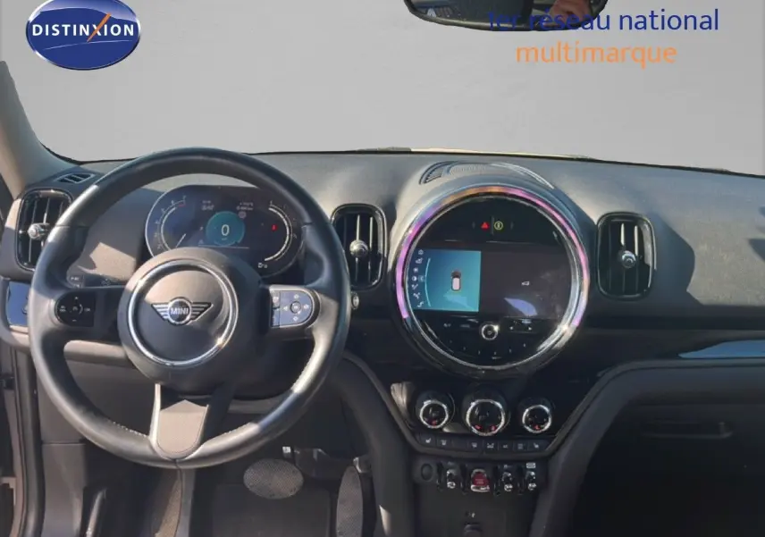 Vue intérieure frontale du tableau de bord et volant noir du MINI Countryman 2023, avec écran central rond allumé.
