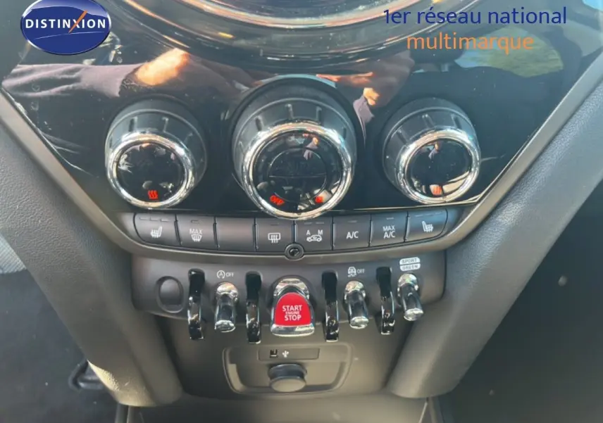 Gros plan sur la console centrale du MINI Countryman 2023, mettant en valeur les commandes de climatisation et le bouton start/stop rouge.