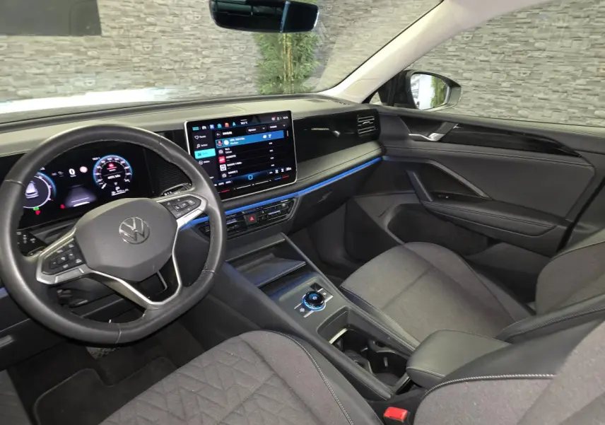 Vue intérieure côté conducteur du Volkswagen Tiguan 2025 avec tableau de bord numérique et sellerie tissu grise.