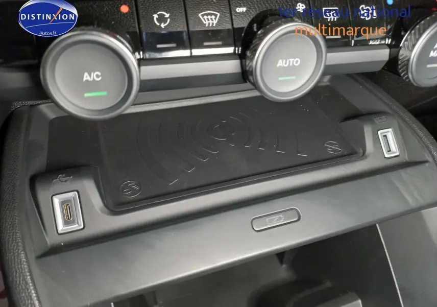 Vue rapprochée de la console centrale du Citroën C4 X 2023 avec commandes climatisation et chargeur sans fil.