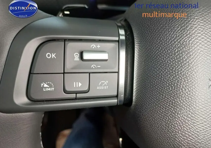 Gros plan sur les commandes de régulateur de vitesse au volant cuir noir du Citroën C4 X gris platinium 2023.