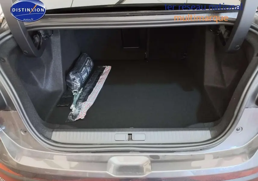 Coffre ouvert d'une Citroën C4 X gris platinium métal, montrant un espace de rangement propre avec kit de sécurité.