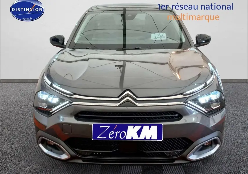 Vue de face d'une Citroën C4 X gris platinium métal avec feux LED allumés et calandre chromée distinctive.