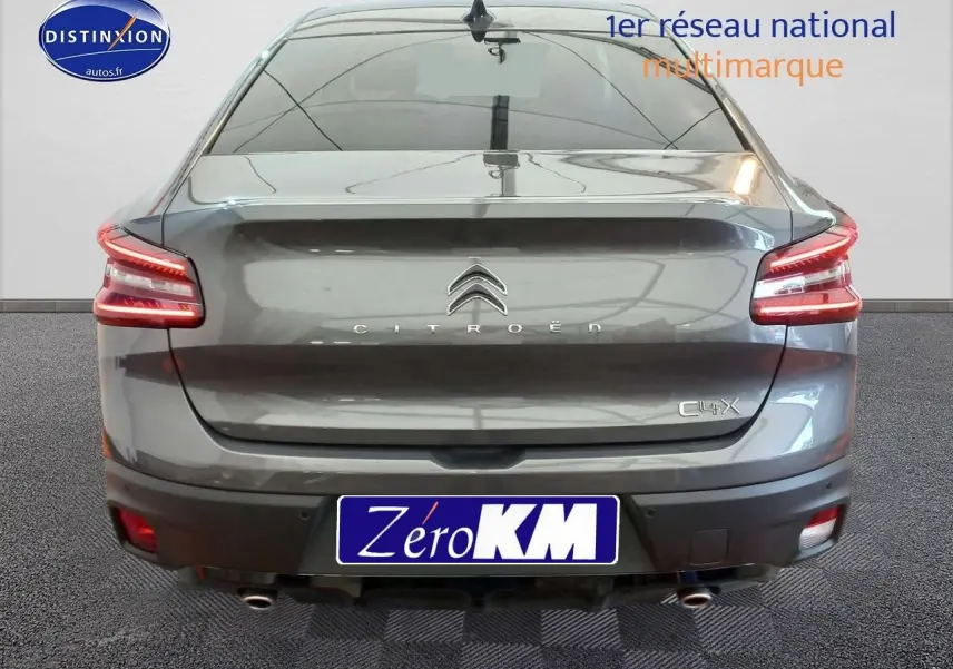 Vue arrière d'une Citroën C4 X gris platinium métal de 2023 avec feux LED et double sortie d'échappement visible.