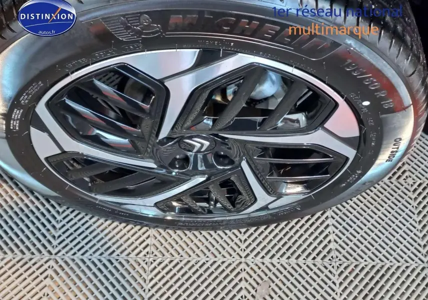 Gros plan sur la jante biton noire et gris platinium d'une Citroën C4 X 2023, pneus Michelin visibles.