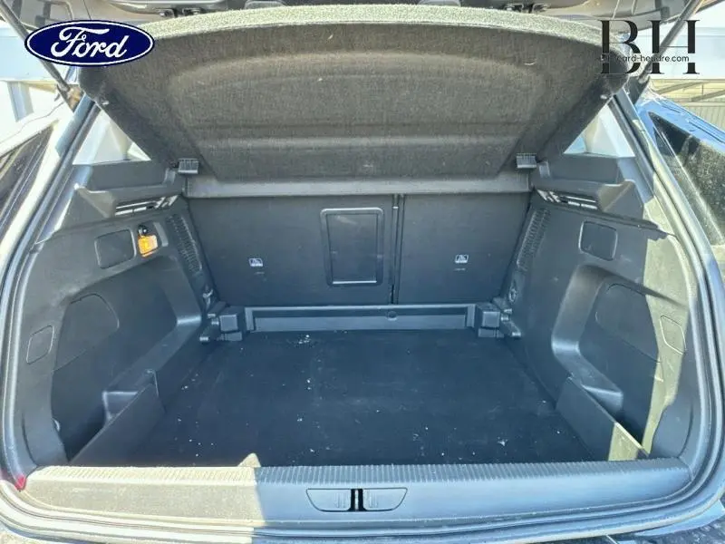 Coffre ouvert vu de l'arrière d'un Opel Grandland noir diamant métallisé, montrant l'espace de chargement et la moquette noire.