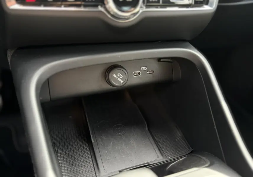 Détail de la console centrale du Volvo XC40 2024 noir Onyx montrant prise 12V et ports USB-C avec recharge sans fil.
