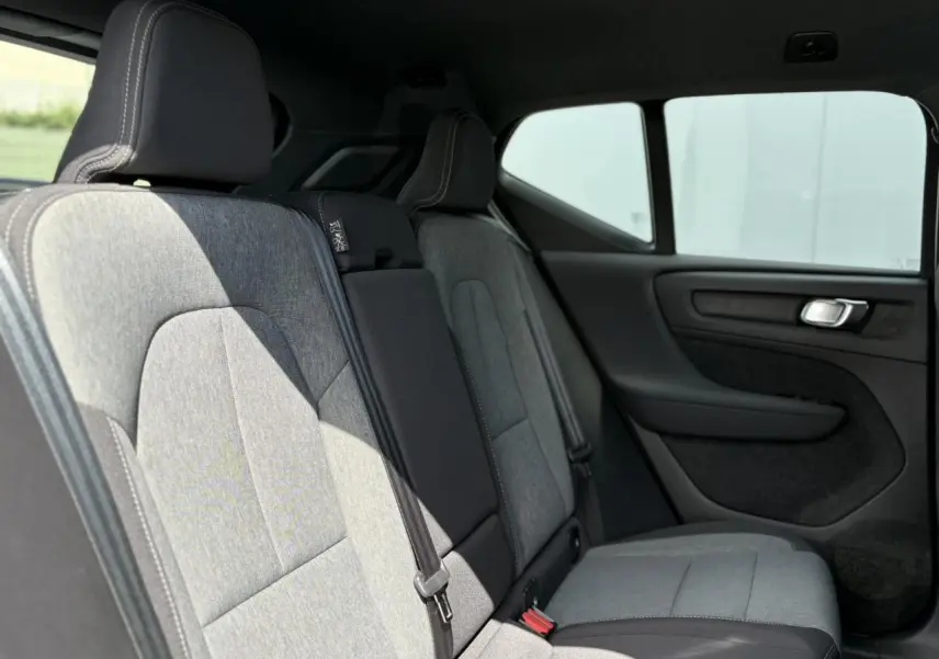 Vue latérale des sièges arrière gris clair du Volvo XC40 B3 MHEV 2024 avec garnitures noires et ceintures visibles.