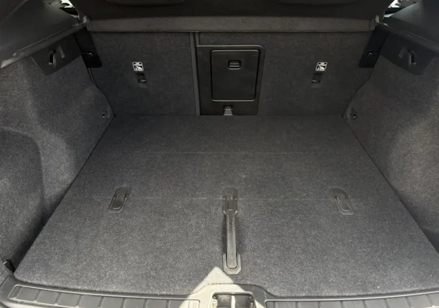 Coffre ouvert du Volvo XC40 B3 MHEV 2024, vue intérieure montrant le tapis gris et la trappe centrale.
