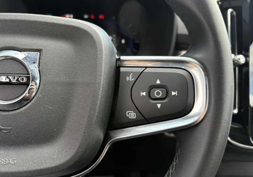 Gros plan sur le volant noir du Volvo XC40 2024 montrant les commandes multifonctions côté droit avec insert chromé.