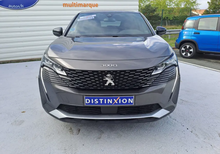 Vue frontale d'un Peugeot 3008 gris platinium 2024 avec calandre noire et logo lion chromé visible.